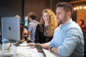 Two members of the Loom PPC team working together at a computer in the Loom office